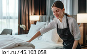 A female maid makes the bed in a hotel room during the day. Toilet concept, shared services, bed, hotel. Стоковое AI-изображение, AI-художник Ярославский Максим / Фотобанк Лори