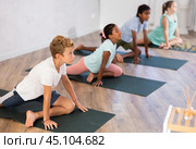 Boy sits in pigeon pose, Eka‑Pada‑Rajakapotasana. Concept of active lifestyle of young generation. Стоковое фото, фотограф Яков Филимонов / Фотобанк Лори