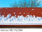 Snow melts from the roof of the house on a spring day. Danger of avalanches from roofs. Snow removal. Стоковое фото, фотограф Коханова Наталья / Фотобанк Лори