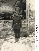 Боец РККА тоит по стойке "смирно" на фоне агитационного плаката, СССР, 1960-е гг. Стоковое фото, фотограф Retro / Фотобанк Лори