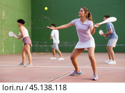 Portrait of sporty girl playing paleta fronton on outdoor court, ready to hit ball. Healthy and active lifestyle concept. Стоковое фото, фотограф Яков Филимонов / Фотобанк Лори
