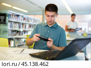 Young european male student plays video games on his phone. Стоковое фото, фотограф Яков Филимонов / Фотобанк Лори