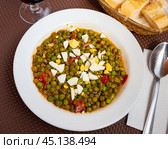 Guisantes a la Murciana - Peas Murcia Style. Juicy peas sauteed with cured ham served with boiled egg on plate, popular Spanish. Стоковое фото, фотограф Яков Филимонов / Фотобанк Лори