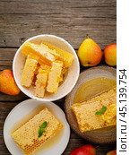honey in honeycomb, close-up, on brown ceramic plate, on old gray wooden rustic table, top view. Стоковое фото, фотограф Natalia Gdovskaia / Фотобанк Лори
