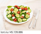 Fresh salad with tomatoes, cucumbers, arugula, mozzarella. Oil with spices, side view, white background. Стоковое фото, фотограф Natalia Gdovskaia / Фотобанк Лори