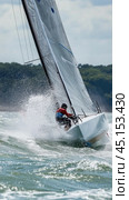 Professional skipper steering sailboat through waves during regatta. Стоковое AI-изображение, AI-художник Юрий Поздников / Фотобанк Лори