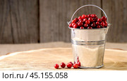 Ripe lingonberries in a decorative bucket on a wooden background. Стоковое фото, фотограф Igor Skripachev / Фотобанк Лори