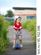 Little girl on scooter with scraped knees on walk. Стоковое фото, фотограф Анна Никонорова / Фотобанк Лори