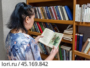 Женщина выбирает книгу для чтения из коллекции библиотеки. Стоковое фото, фотограф Александр Бушков / Фотобанк Лори