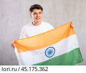 Happy young man holding flag of India against unicoloured background. Стоковое фото, фотограф Яков Филимонов / Фотобанк Лори