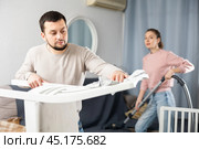 Man wiping furniture with rag while woman hoovering couch. Стоковое фото, фотограф Яков Филимонов / Фотобанк Лори