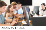 Interested young girl attending computer class, learning digital technology under guidance of positive adult male teacher standing nearby. Стоковое видео, видеограф Яков Филимонов / Фотобанк Лори