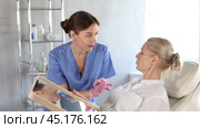 Old woman patient lying on clinical chair discussing face aesthetic procedures with doctor. Стоковое видео, видеограф Яков Филимонов / Фотобанк Лори