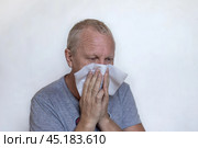 An elderly European man blows his nose, sneezes and coughs into a napkin. Coronavirus infection. Стоковое фото, фотограф Коханова Наталья / Фотобанк Лори