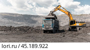 Large quarry dump excavator. Big yellow mining excavator at work site. Loading coal into body truck. Mining digger, mining machinery to loading rock. Production useful minerals. Стоковое фото, фотограф Сергей Тимофеев / Фотобанк Лори