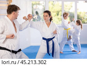Determined female karateka working on hand strikes in sparring with husband. Стоковое фото, фотограф Яков Филимонов / Фотобанк Лори
