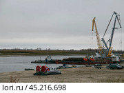 Берег Иртыша, погрузка грузов и техники на баржи в конце сезона навигации в Югре. Редакционное фото, фотограф Илья Юрукин / Фотобанк Лори
