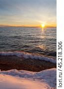 Baikal Lake in December at sunset. Snowy beach in Listvyanka village against backdrop of setting sun. Scenic seascape. Natural background. Outdoor recreation and travel along the lake shore. Стоковое фото, фотограф Виктория Катьянова / Фотобанк Лори