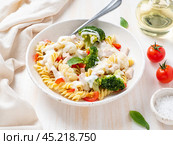 Pasta fusilli with vegetables, boiled steamed meat, white sauce on white wooden table. Стоковое фото, фотограф Natalia Gdovskaia / Фотобанк Лори