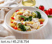 Pasta fusilli with vegetables, boiled steamed meat, white sauce on white wooden table, low-calorie diet, low-fat diet, side view. Стоковое фото, фотограф Natalia Gdovskaia / Фотобанк Лори