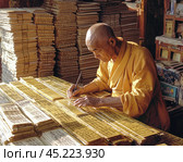 Buddhist monk hand-writing scriptures surrounded by ancient texts. Стоковое AI-изображение, AI-художник Юрий Поздников / Фотобанк Лори