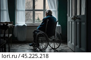 A lonely old man sits in a wheelchair and looks out the window. Loneliness and old age. lonely elder thoughtful sad old man look outside windows in bedroom at retirement home. Generative AI. Стоковое AI-изображение, AI-художник Sergey Grishin / Фотобанк Лори