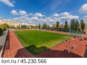 Znamensky Brothers stadium, Stromynka 4 - 03.09.2019: An athletic track showcases bright red lanes adjacent to a modern building, surrounded by green trees and a blue sky filled with fluffy clouds during a sunny day. Стоковое фото, фотограф Алексей Климкин / Фотобанк Лори