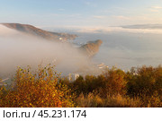 Петропавловск-Камчатский, Камчатский край, Россия. Красивый вечерний городской пейзаж. Вид сверху с Мишенной сопки на побережье Авачинской бухты и Никольскую сопку. Низкая облачность и туман скрывают историческую часть города. Вечернее золотистое освещение на закате. Путешествие на Камчатку. Дальний Восток России. Стоковое фото, фотограф Андрей Степанов / Фотобанк Лори
