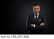 Successful businessman with crossed arms in magnificent suit stands on dark background. portrait of charismatic billionaire. Стоковое AI-изображение, AI-художник Павел Муравьев / Фотобанк Лори