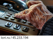 Senior woman dialing number on old phone. Стоковое AI-изображение, AI-художник Иван Рябоконь / Фотобанк Лори