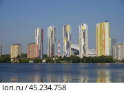 Several tall apartment buildings with colorful facades stand along the shore of a calm body of water. The buildings are tall and slender, and the water is a deep blue. Стоковое фото, фотограф Алексей Климкин / Фотобанк Лори