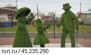 Talmenka, Russia-October, 26,2024. Sculptures. Figures of a woman with an umbrella, a girl and a man in a hat made of artificial turf are on a city street. Siberia. Редакционное видео, видеограф Сергей Медведев / Фотобанк Лори