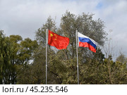 Развевающиеся флаги Российской Федерации и Китайской Народной Республики. Стоковое фото, фотограф syngach / Фотобанк Лори