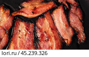 Frying Bacon Slices in a Pan. Crispy Pieces of Delicious Red Thin Smokey Bacon Fried in a Hot Skillet. Traditional Breakfast. Smoked Bacon Rasher or Strip Being Cooked. Grill. Fat High Calorie Food. Стоковое видео, видеограф Марина Демидюк / Фотобанк Лори