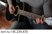 Playing the guitar. Strumming black acoustic guitar. Musician plays music. Man fingers holding mediator. Male hand playing guitar neck in dark room. Unrecognizable person rehearsing, fretboard closeup. Стоковое видео, видеограф Марина Демидюк / Фотобанк Лори