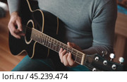 Playing the guitar. Strumming black acoustic guitar. Musician plays music. Man fingers holding mediator. Male hand playing guitar neck in dark room. Unrecognizable person rehearsing, fretboard closeup. Стоковое видео, видеограф Марина Демидюк / Фотобанк Лори