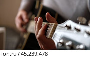Playing the guitar. Strumming black acoustic guitar. Musician plays music. Man fingers holding mediator. Male hand playing guitar neck in dark room. Unrecognizable person rehearsing, fretboard closeup. Стоковое видео, видеограф Марина Демидюк / Фотобанк Лори