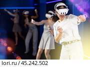 Emotional girls in VR headsets fully immersed in game, engaged in virtual reality world, manipulating objects or shooting targets with joysticks in hands. Стоковое фото, фотограф Яков Филимонов / Фотобанк Лори