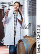 Female employee in white robe posing at winery. Стоковое фото, фотограф Татьяна Яцевич / Фотобанк Лори