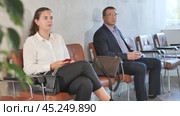 Serious-minded female candidate siting on chair and waiting for job interview in hallway. Стоковое видео, видеограф Яков Филимонов / Фотобанк Лори