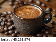 A cup of freshly brewed coffee with thick foam on the surface, standing on a wooden surface. Coffee beans are scattered nearby, which emphasizes the naturalness and aroma of the drink. The ceramic cup has a textured surface, which adds coziness and warmth to the composition. The photo conveys an atmosphere of relaxation and pleasure from enjoying morning coffee. Стоковое AI-изображение, AI-художник Анна Кривицкая / Фотобанк Лори