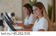 Receptionists assisting guests at a hotel front desk during a busy morning shift with computers and friendly smiles. Стоковое AI-изображение, AI-художник Сергей Толмачёв / Фотобанк Лори