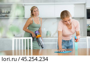 Teenage girl wiping table with rag and detergent at home kitchen. Стоковое фото, фотограф Яков Филимонов / Фотобанк Лори