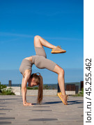 Fitness portrait young athletic woman doing gymnastics on blue sky background. Стоковое фото, фотограф Андрей Аркуша / Фотобанк Лори