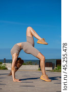 Fitness portrait young athletic woman doing gymnastics on blue sky background. Стоковое фото, фотограф Андрей Аркуша / Фотобанк Лори