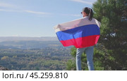 The Russian flag is on the shoulders of a girl standing against the backdrop of the Caucasus mountains. Unity Day in Russia. Стоковое видео, видеограф Екатерина Золина / Фотобанк Лори