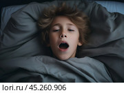 cold tones, boy in t shirt lied in bed under blanket and yawns or very emotional expression sings songs with wide opened mouth and squint eyes. Стоковое AI-изображение, AI-художник Sergey Grishin / Фотобанк Лори