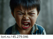 Portrait of Asian angry, sad and cry little boy on dirty grey color background, The emotion of a child when tantrum and mad, expression grumpy emotion, yelling, shouting. Kid emotional control concept. Стоковое AI-изображение, AI-художник Sergey Grishin / Фотобанк Лори
