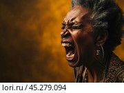 Closeup portrait, mad, angry, upset, hostile, senior african american mature woman, worker, furious employee, yelling, open mouth, yellow background. Negative human emotions, facial expression. Стоковое AI-изображение, AI-художник Sergey Grishin / Фотобанк Лори