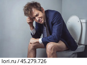 Man in a suit sits on a toilet in a restroom and suffers from diarrhea. Стоковое AI-изображение, AI-художник Дмитрий Киселёв / Фотобанк Лори